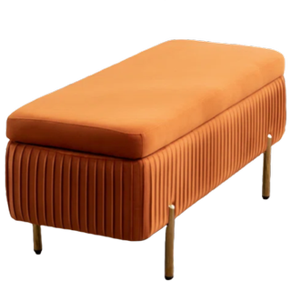 an orange velvet upholstered storage bench on thin wooden legs