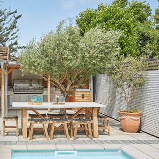 white table on patio next to swimming pool, with stools