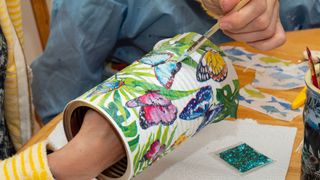 A person using decoupage techniques to decorate an old vase