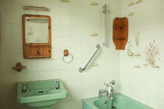 A dated bathroom with an avocado suite bath, discolored wall tiles, and wooden cabinetry