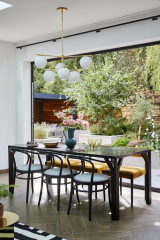 Dining table and chairs set by bifold doors looking out to garden