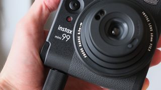 Close up of the logo of an Fujifilm Instax Mini 99 instant camera held in a hand