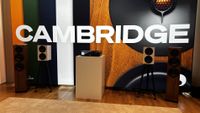 Cambridge Audio Evo 300 in the middle of a room flanked by two pairs of speakers. A bright white Cambridge logo is in the background