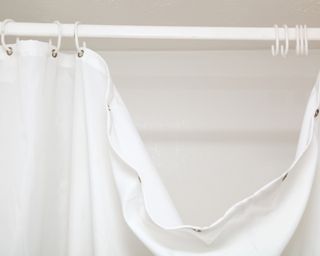 White plastic shower curtain draping off curtain rod