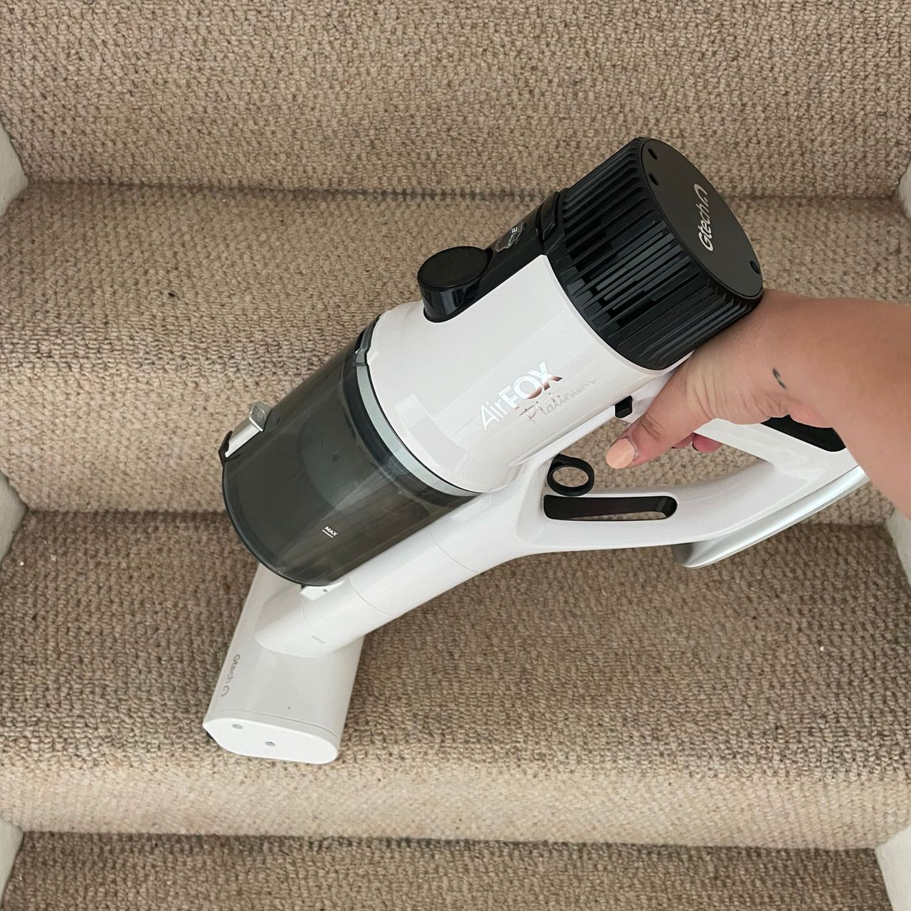 Gtech AirFOX Platinum Cordless Vacuum in handheld mode vacuuming carpeted stairs