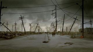 A promotional image from the movie The Road. It shows two distant figures walking along a decimated highway.