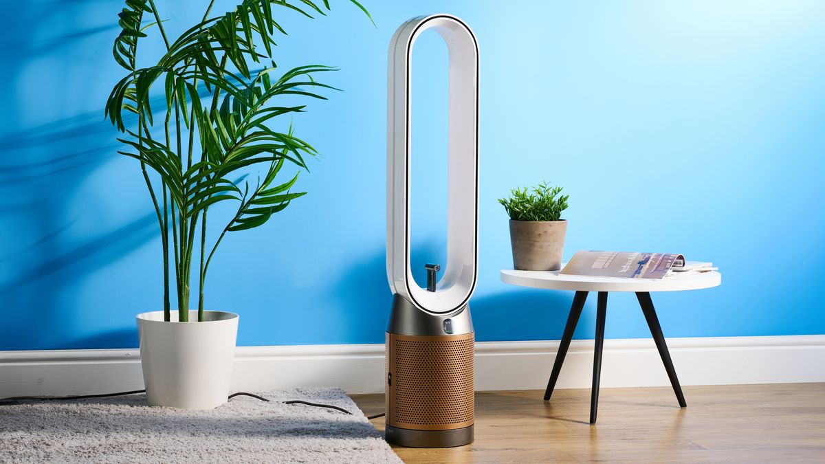 The Dyson Find+Follow Purifier Cool PC3 in a lounge with a blue wall in the background