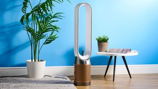 The Dyson Find+Follow Purifier Cool PC3 in a lounge with a blue wall in the background