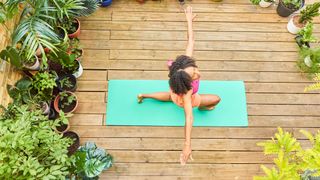 Woman doing yoga surrounded by plants.