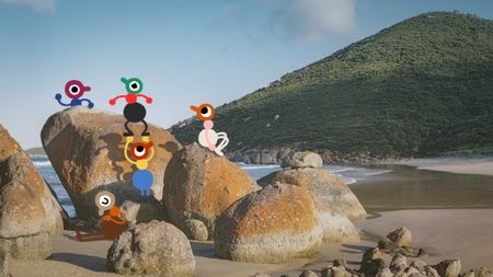 A group of Big Walk characters explore a pile of rocks on a beach