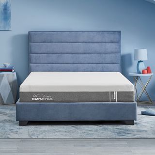 A TEMPUR-Cloud mattress on a bed against a blue wall.