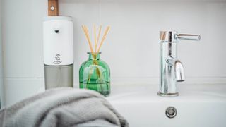 A diffuser next to a sink and soap dispenser