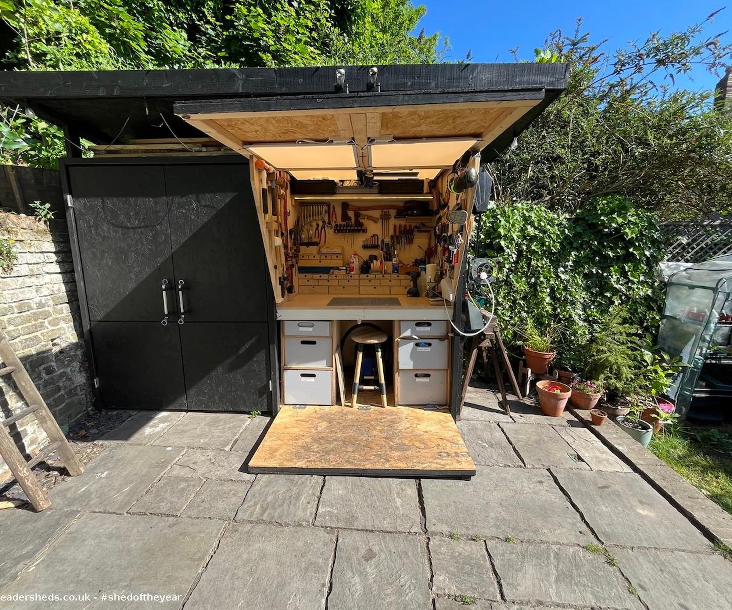 A workshop shed in black paint and black storage and lights