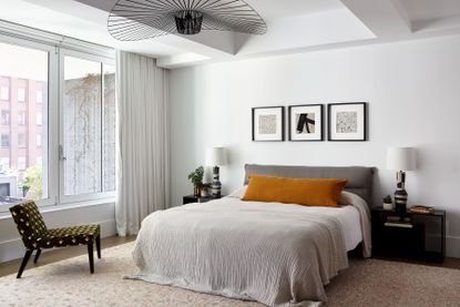A mid-century modern style bedroom with a grey headboard and mustard yellow cushions