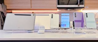 Samsung Galaxy FE-serien med mobiler, nettbrett og ørepropper på et utstillingsbord-