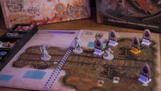 The scenario book, map, models, and box of Gloomhaven: Jaws of the Lion on a wooden table