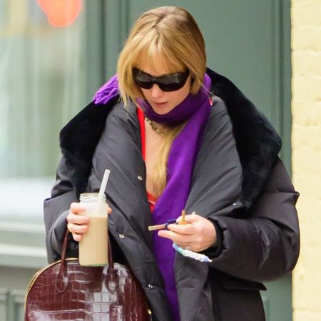 Jennifer lawrence wears black sunglasses, a purple scarf, black puffer jacket, and a brown croc bag.