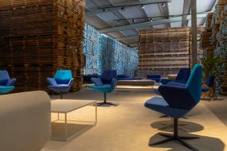 Prostoria showroom interior with walls made of stacked wooden planks. On display are a series of chairs upholstered in different shades of blue textile