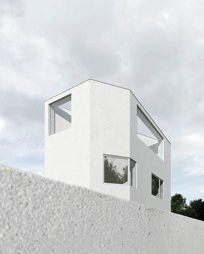 External view of a modern white building looming out from behind a wall in the foreground