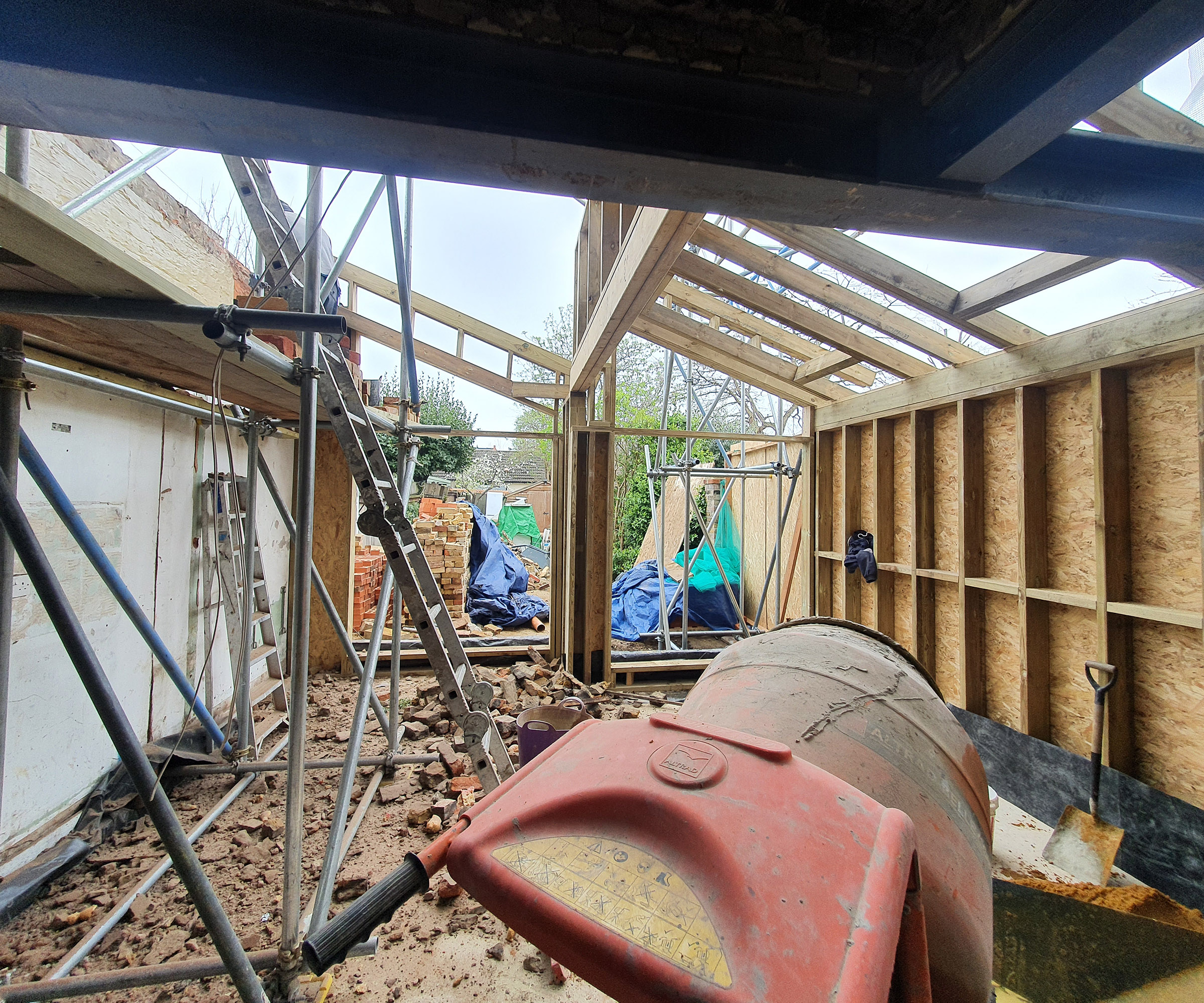Construction of a kitchen extension with sips panels and a cement mixer in the foreground