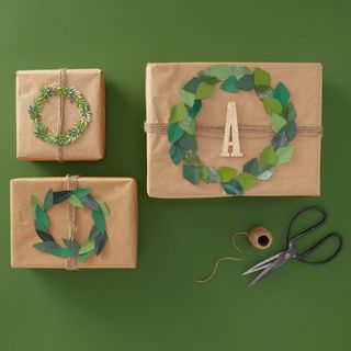 3 gifts wrapped in brown wrapping paper with foliage decorations and tags