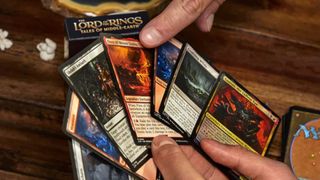 A hand points to Magic: The Gathering cards someone is holding