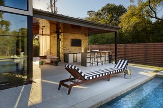 Patio furniture ideas in a modern yard with swimming pool, featuring a double monochrome striped sun lounger.