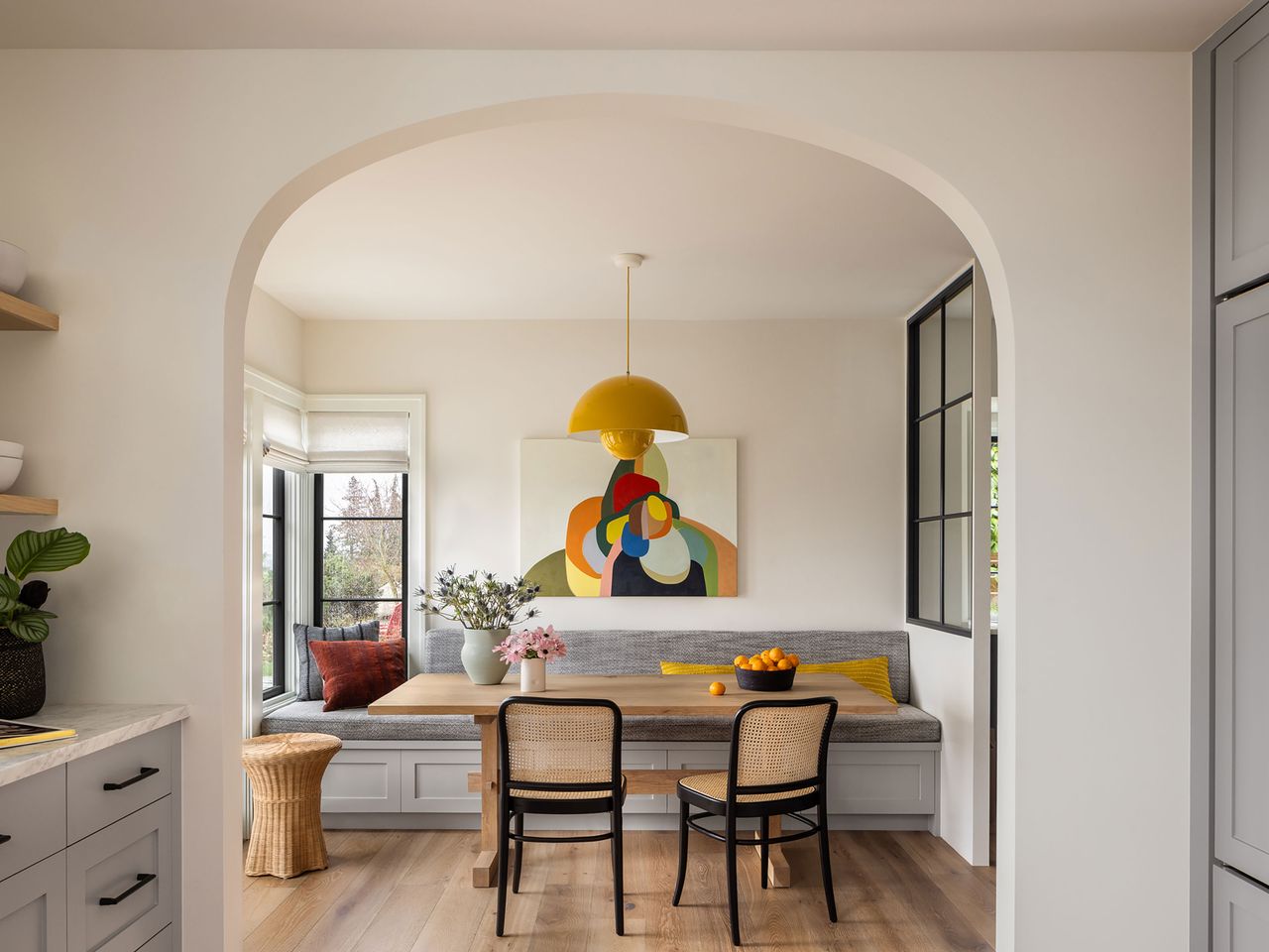 breakfast nook with gray bench seat and bright artwork above and glass screened partition