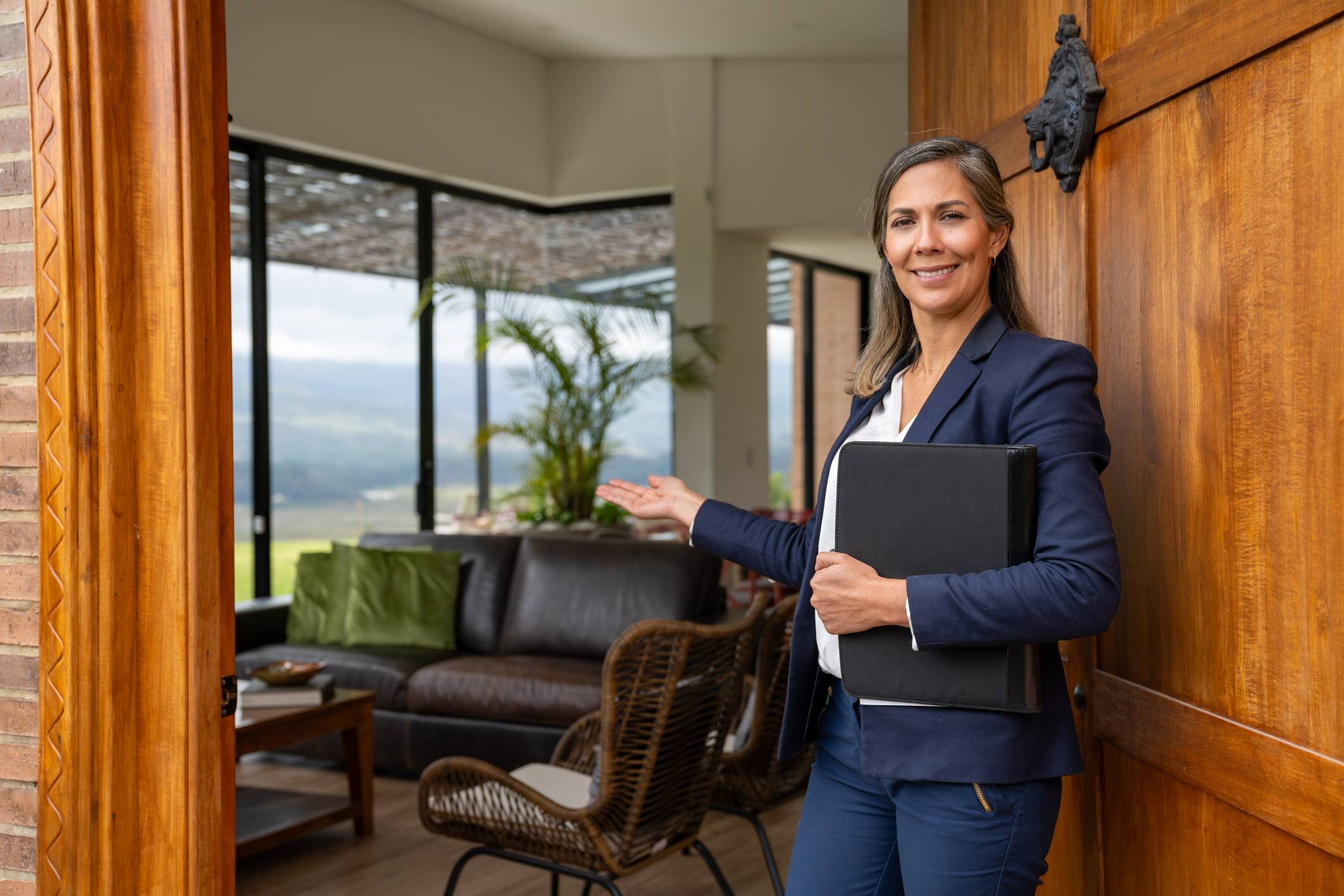 Real estate agent welcoming clients for a house showing and looking at the camera smiling &amp;ndash; POV concepts