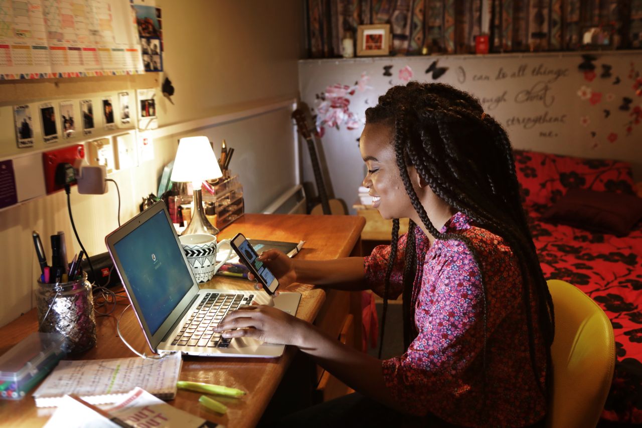 Woman working in university halls with laptop and phone