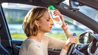 woman in hot car with water bottle held to her head