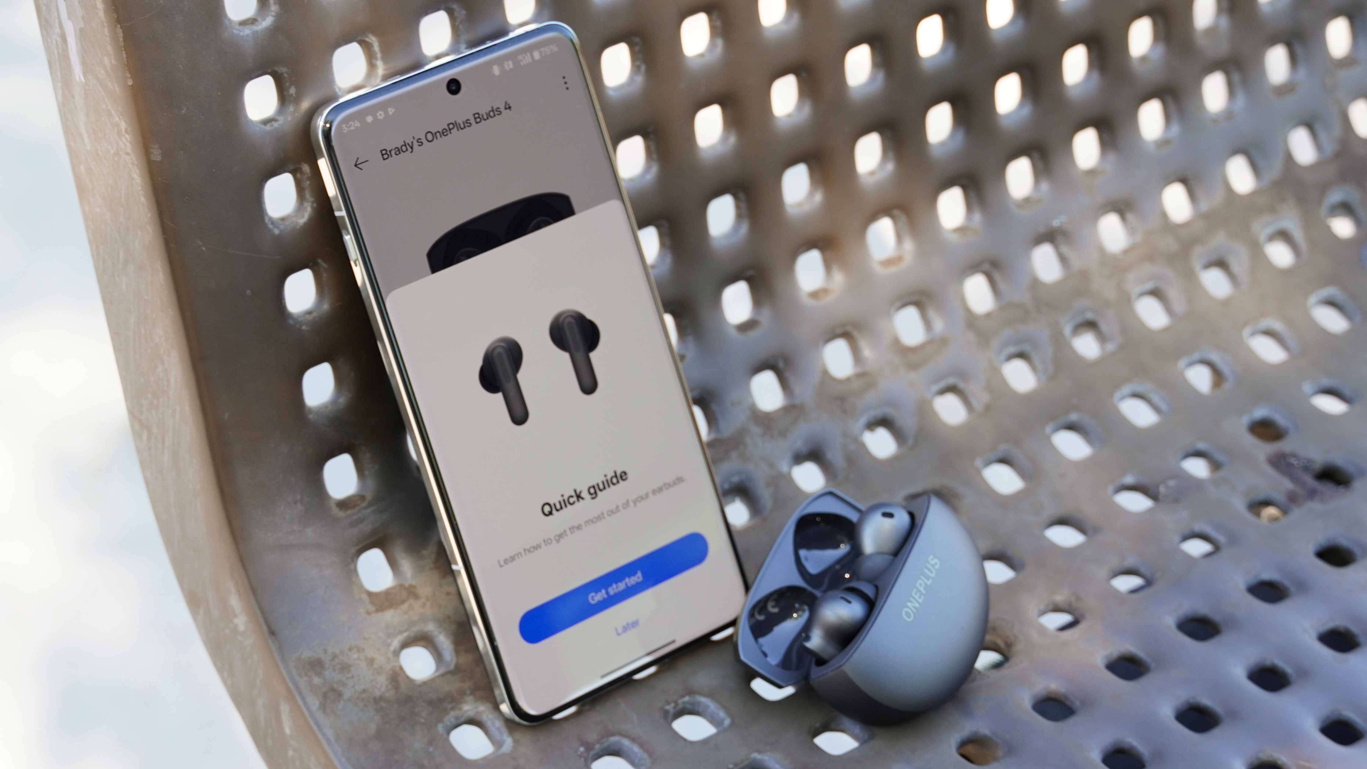The OnePlus Buds 4 in Storm Gray beside their app controls running on a OnePlus 13.