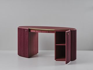 Burgundy desk with oval shape and cabinets concealed in the thick legs