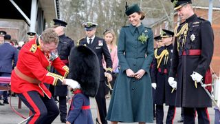 Britain's Catherine, Duchess of Cambridge (2R) and Britain's Prince William, Duke of Cambridge, laugh as Lieutenant Colonel Rob Money puts a bearskin hat on his 20-month-old daughter Gaia Money, during their visit to the 1st Battalion Irish Guards for their St Patrick's Day Parade, at Mons Barracks in Aldershot, south west of London, on March 17, 2022.