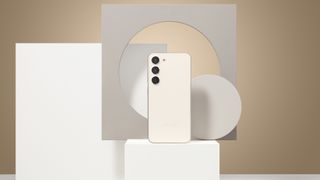 Samsung Galaxy S23 on a white pedestal surrounded by shapes with a beige backdrop