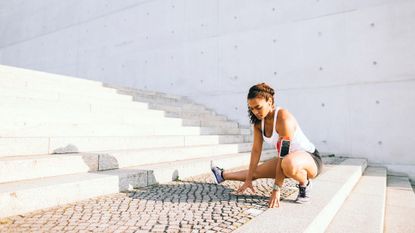runner stretching before a workout outside while listening to music