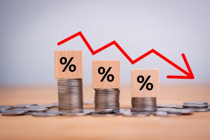 Percentage sign on wooden cubes with Stack of coin bar chart and red graph trending downwards on white background. Economy recession crisis, inflation, stagflation, business and financial loss concept