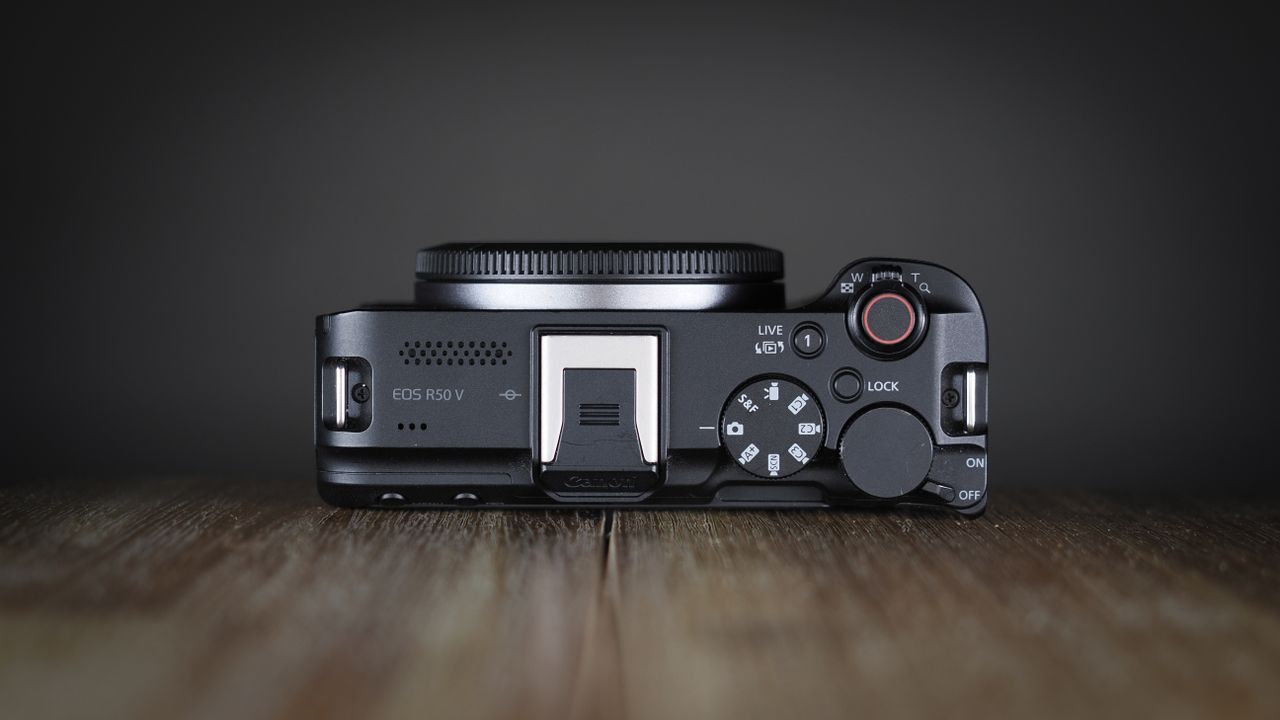 Canon EOS R50 V on a wooden surface, against a dark background