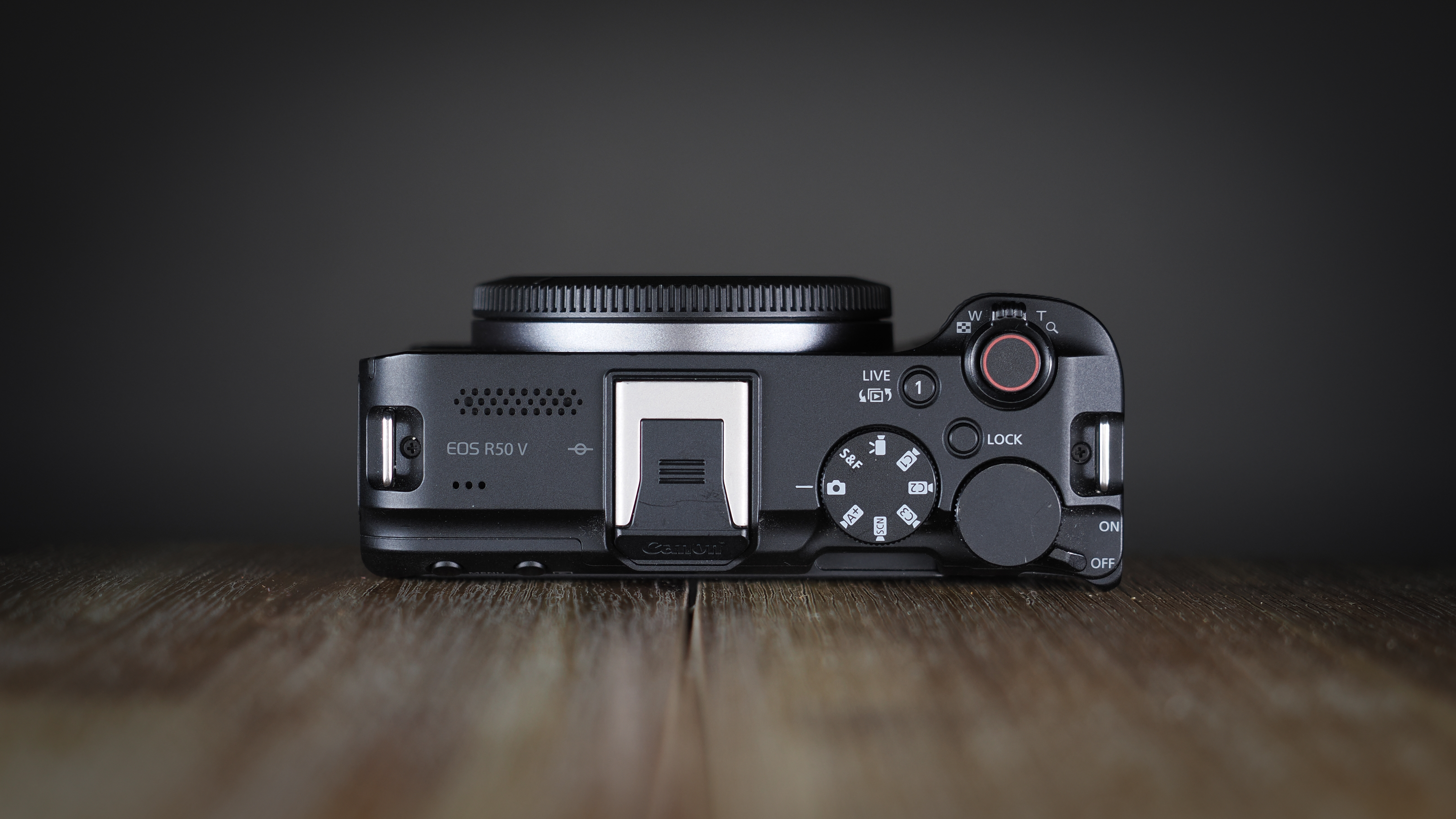 Canon EOS R50 V on a wooden surface, against a dark background