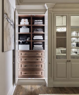 Walk in closet with cream doors and wooden drawers with built in lights