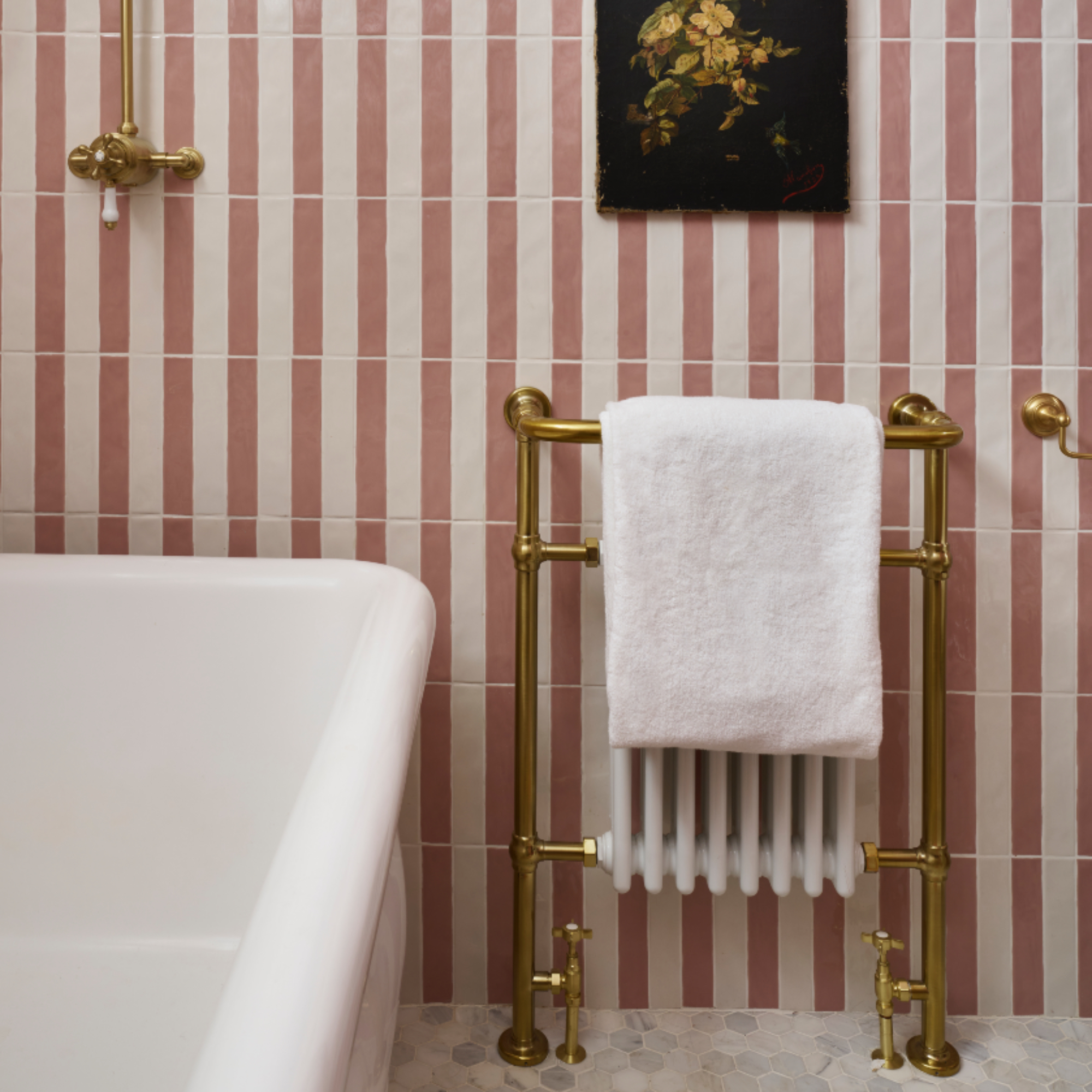 Pearl Lowe's bathroom with brass Victorian style radiator, vintage artwork, white towel, bath