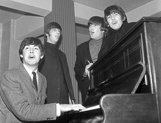 the Beatles stood around a piano singing