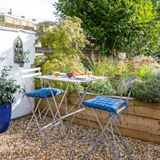 Balcony with metal bistro set beside raised beds