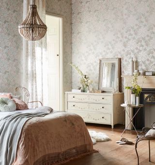 Romantic bedroom with white vintage chest, delicate linen and white patterned wallpaper