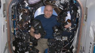 Astronaut Don Pettit floats aboard the ISS with several cameras and lenses