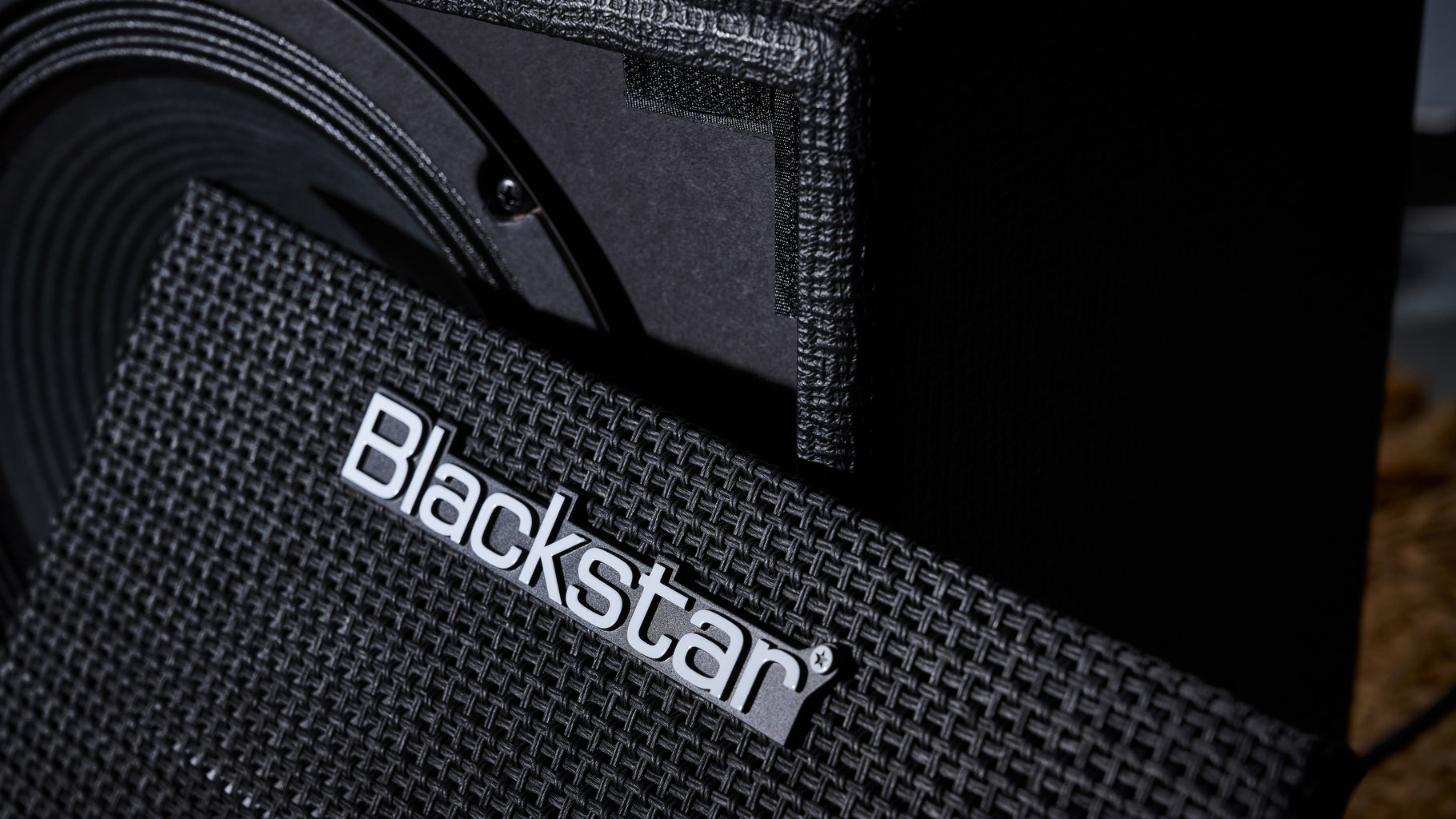 Blackstar Debut Bass 25: this compact little combo is finished in black with matching grille clothe and is photographed in close-up against a stone floor and weaved rug.