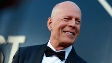 Bruce Willis wears a tuxedo and bow tie in front of a blue background. He was attending the Comedy Central Roast of Bruce Willis at Hollywood Palladium on July 14, 2018 in Los Angeles, California.