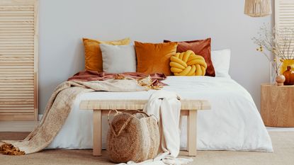 autumn decor bedroom with orange throw pillows and blankets on white bedding