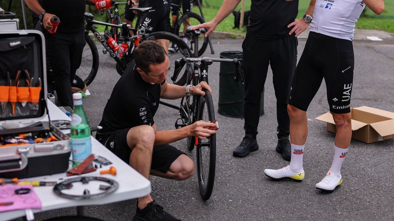 UAE Team EmirGeates&#039; Slovenian rider Tadej Pogacar (R) looks on as team mechanics adjust his bicycle before taking part in a team training session, on June 29, 2023