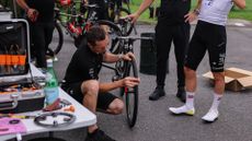 UAE Team EmirGeates' Slovenian rider Tadej Pogacar (R) looks on as team mechanics adjust his bicycle before taking part in a team training session, on June 29, 2023